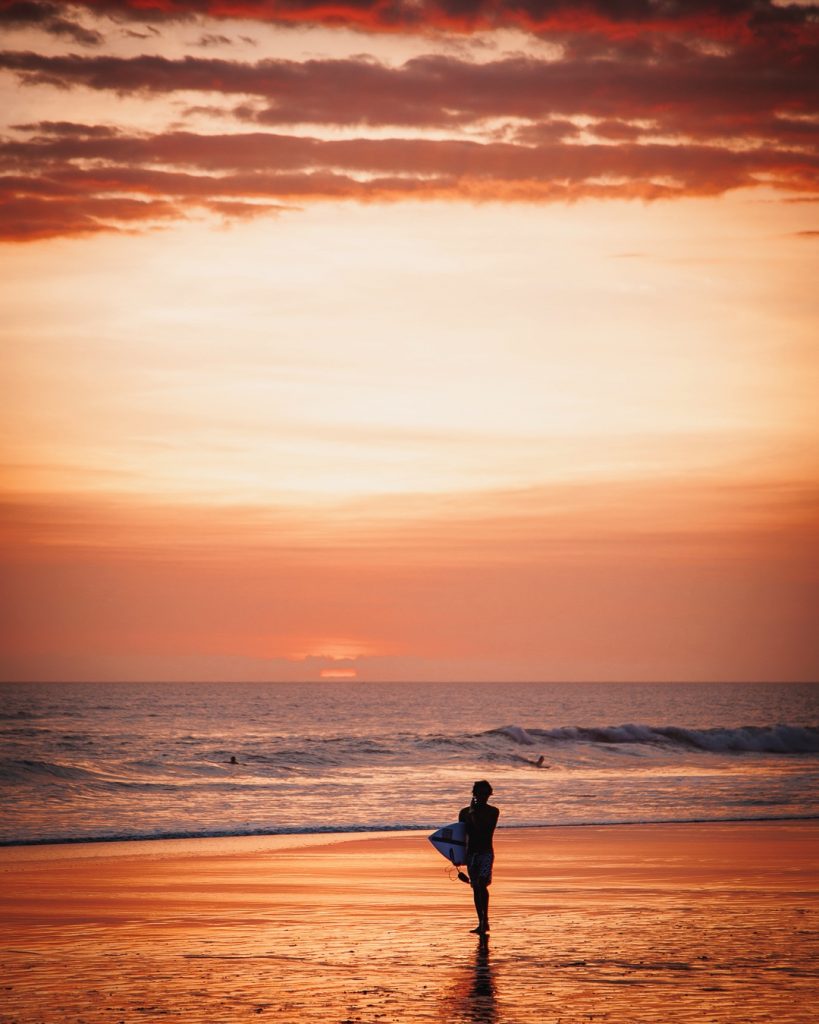 Bali zonsondergang op strand met surfer in zee reisfotografie indonesie